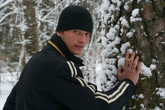 Beautiful young boy posing outdoors with trees