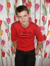 Brown-eyed young boy posing shirtless next to a wall