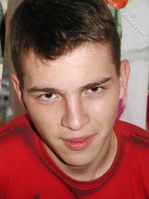 Brown-eyed young boy posing shirtless next to a wall