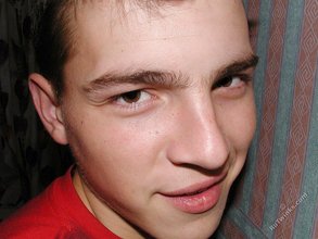 Brown-eyed young boy posing shirtless next to a wall