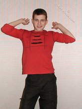 Brown-eyed young boy posing shirtless next to a wall