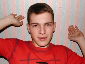 Brown-eyed young boy posing shirtless next to a wall