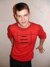 Brown-eyed young boy posing shirtless next to a wall