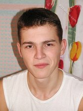 Brown-eyed young boy posing shirtless next to a wall