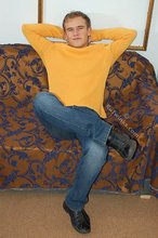 Thoughtful twink shows his six pack on a couch