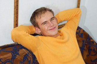 Thoughtful twink shows his six pack on a couch