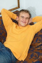 Thoughtful twink shows his six pack on a couch