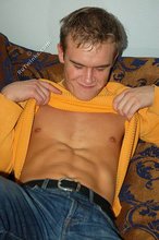Thoughtful twink shows his six pack on a couch