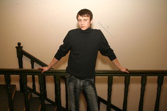 Dark-haired dude with beautiful eyes poses in his room