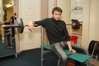 Dark-haired dude with beautiful eyes poses in his room