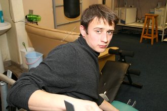 Dark-haired dude with beautiful eyes poses in his room