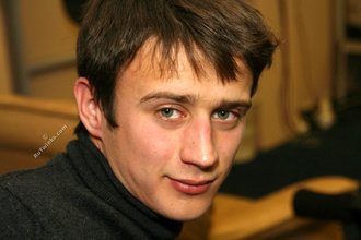 Dark-haired dude with beautiful eyes poses in his room