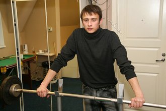 Dark-haired dude with beautiful eyes poses in his room