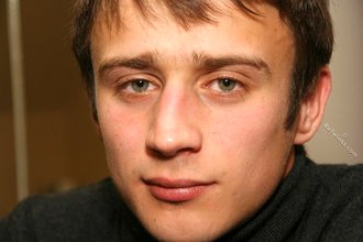 Dark-haired dude with beautiful eyes poses in his room