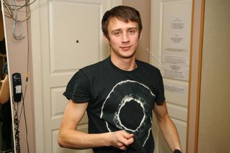 Dark-haired dude with beautiful eyes poses in his room