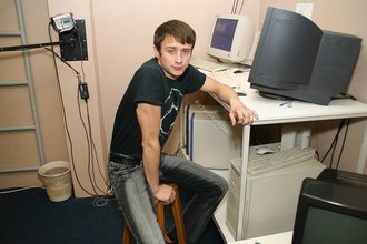 Dark-haired dude with beautiful eyes poses in his room