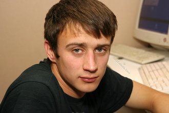 Dark-haired dude with beautiful eyes poses in his room