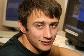 Dark-haired dude with beautiful eyes poses in his room