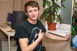 Dark-haired dude with beautiful eyes poses in his room