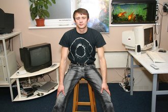 Dark-haired dude with beautiful eyes poses in his room