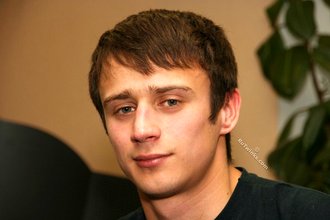 Dark-haired dude with beautiful eyes poses in his room