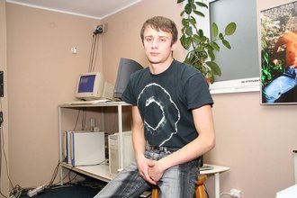 Dark-haired dude with beautiful eyes poses in his room
