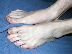 Dark-haired twink with piercing eyes showing his feet