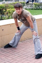 Athletic dude in oversized jeans is doing handstands outdoors