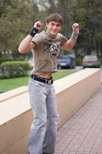Athletic dude in oversized jeans is doing handstands outdoors