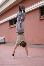 Athletic dude in oversized jeans is doing handstands outdoors
