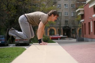 Athletic dude in oversized jeans is doing handstands outdoors
