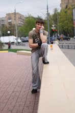 Athletic dude in oversized jeans is doing handstands outdoors