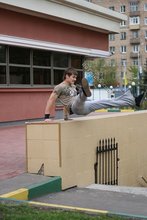 Athletic dude in oversized jeans is doing handstands outdoors