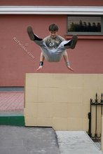 Athletic dude in oversized jeans is doing handstands outdoors