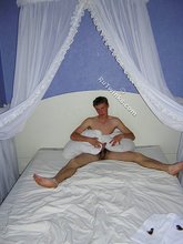 Red-faced twink nerd posing on a white bed