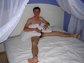 Red-faced twink nerd posing on a white bed