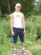 Baseball cap and jorts-wearing twink posing outdoors