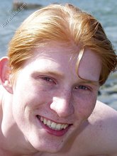 Redheaded twink posing in his sexy shades on a beach