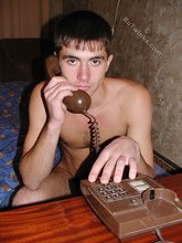 Short-haired twink boy posing on his knees on a bed
