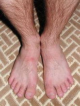 Short-haired twink boy posing on his knees on a bed