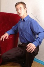 Serious-looking young boy starts undressing on cam