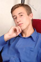 Serious-looking young boy starts undressing on cam