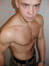 Blond-haired boy posing shirtless in his camo pants