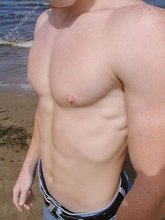 Redheaded guy posing shirtless in the woods