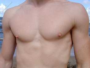 Redheaded guy posing shirtless in the woods