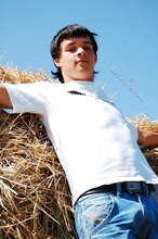 Dark-haired young twink posing in a haystack