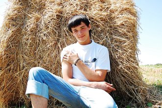 Dark-haired young twink posing in a haystack
