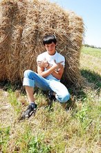 Dark-haired young twink posing in a haystack