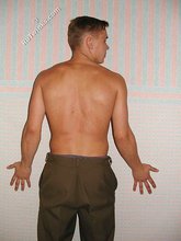 Jacked-up twink posing shirtless by the wall