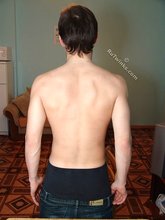 Dark-haired young boy shows off his body by the table